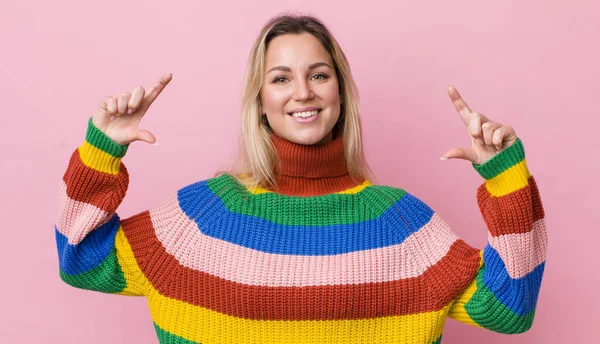 pretty blonde woman framing or outlining own smile with both hands, looking positive and happy, wellness concept