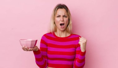 Sarışın, güzel bir kadın sinirli bir ifadeyle agresif bir şekilde bağırıyor. boş kase kavramı