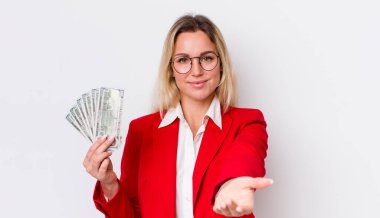 Sarışın, güzel bir kadın mutlu bir şekilde gülümsüyor ve bir konsept sunuyor. Dolar banknotları konsepti