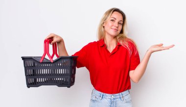 Sarışın, güzel kadın şaşkın, şaşkın ve şüpheci hissediyor. Alışveriş sepeti konsepti