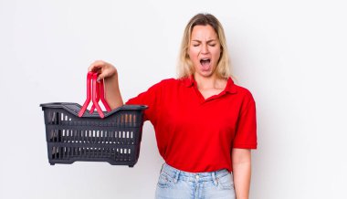 Sarışın, güzel bir kadın agresif bir şekilde bağırıyor, çok kızgın görünüyor. Alışveriş sepeti konsepti