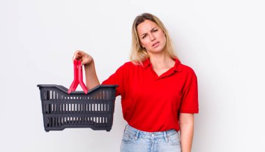 Sarışın, güzel kadın kafası karışık ve şaşkın hissediyor. Alışveriş sepeti konsepti