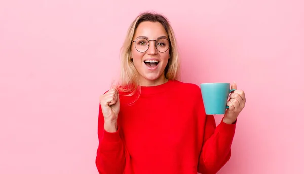 ブロンドの女はショックを受けて笑って成功を祝ってる コーヒーカップのコンセプト — ストック写真