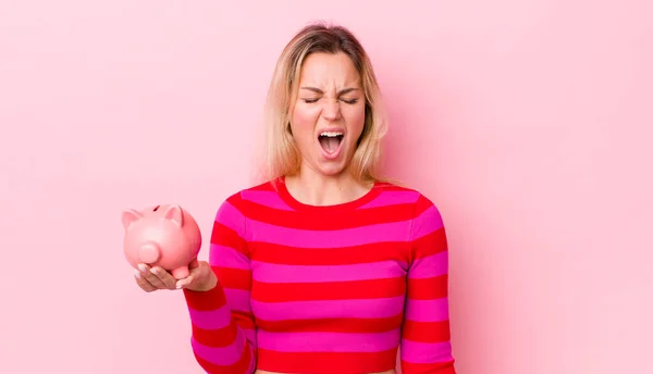 Blonde Pretty Woman Shouting Aggressively Looking Very Angry Piggy Bank — Stockfoto