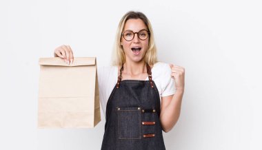 Sarışın, güzel bir kadın şokta, gülüyor ve başarıyı kutluyor. teslimat paket servis kavramı