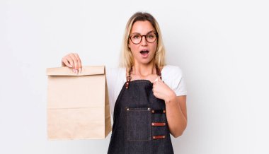 Sarışın, güzel bir kadın kendini mutlu hissediyor ve heyecanlı bir şekilde kendini işaret ediyor. teslimat paket servis kavramı