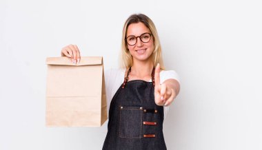 Sarışın, güzel bir kadın gururla gülümsüyor ve kendinden emin bir numara oluyor. teslimat paket servis kavramı