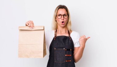 Sarışın, güzel bir kadın inançsızlıktan şaşkın şaşkın bakıyor. teslimat paket servis kavramı