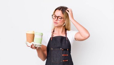 Kafası karışmış, kafası karışmış, kaşınan güzel sarışın bir kadın. kahve konseptini kaldır.