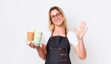 Sarışın, güzel bir kadın gülümsüyor ve arkadaş canlısı görünüyor. Beş numarayı gösteriyor. kahve konseptini kaldır.