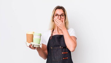 Sarışın, güzel bir kadın, elleri ve ağzı şok olmuş bir şekilde kapatıyor. kahve konseptini kaldır.