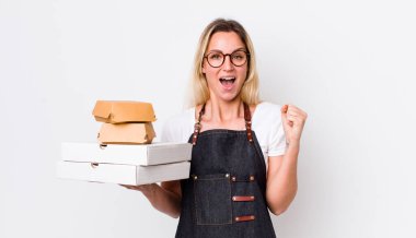 Sarışın, güzel bir kadın şokta, gülüyor ve başarıyı kutluyor. Fast food konseptini kaldır.