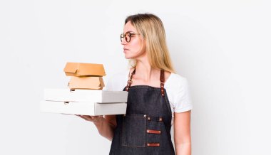 Profil bakışlı sarışın güzel kadın hayal mi kuruyor yoksa hayal mi kuruyor? Fast food konseptini kaldır.