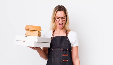 Sarışın, güzel bir kadın agresif bir şekilde bağırıyor, çok kızgın görünüyor. Fast food konseptini kaldır.