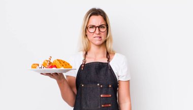 Şaşkın ve kafası karışmış sarışın güzel bir kadın. Waffle konsepti