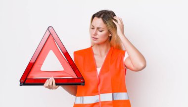 Kafası karışmış, kafası karışmış, kaşınan güzel sarışın bir kadın. araba üçgeni kaza konsepti