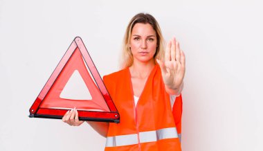 Sarışın, güzel bir kadın ciddi görünüyor. Avuç içi gösteriyor. Durma hareketi yapıyor. araba üçgeni kaza konsepti