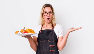 Güzel sarışın kadın şaşırmış ve şok olmuş görünüyor. Çenesi düşmüş ve elinde bir nesne var. Waffle konsepti