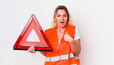 Sarışın, güzel bir kadın kendini mutlu hissediyor ve heyecanlı bir şekilde kendini işaret ediyor. araba üçgeni kaza konsepti