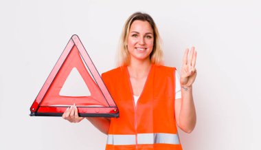 Sarışın, güzel bir kadın gülümsüyor ve arkadaş canlısı görünüyor, üç numarayı gösteriyor. araba üçgeni kaza konsepti