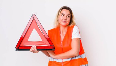 Sarışın, güzel bir kadın omuz silkiyor, kafası karışık ve kararsız. araba üçgeni kaza konsepti