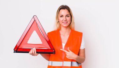 Sarışın, güzel bir kadın neşeyle gülümsüyor, mutlu hissediyor ve bir tarafı işaret ediyor. araba üçgeni kaza konsepti