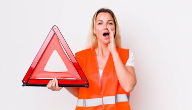 Sarışın, güzel bir kadın kendini mutlu hissediyordu. Elleri ağzının kenarında bağırıyordu. araba üçgeni kaza konsepti