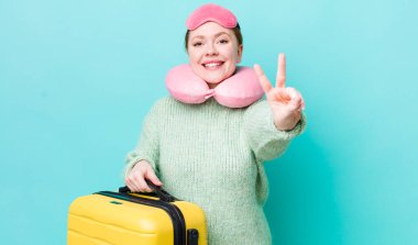 Kızıl saçlı güzel kadın gülümsüyor ve mutlu görünüyor, zafer ya da barış işareti yapıyor. uçuş yolcu kavramı