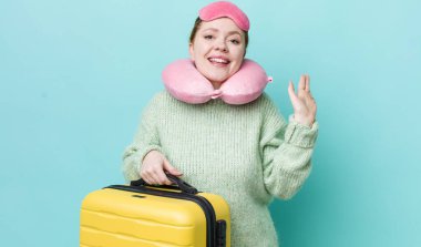 Kızıl saçlı güzel kadın mutlu bir şekilde gülümsüyor, el sallıyor, seni selamlıyor ve selamlıyor. uçuş yolcu kavramı