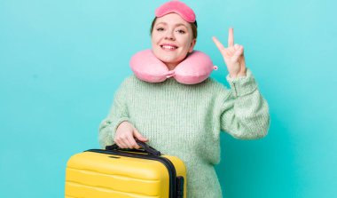 Kızıl saçlı güzel kadın gülümsüyor ve arkadaş canlısı görünüyor, iki numarayı gösteriyor. uçuş yolcu kavramı