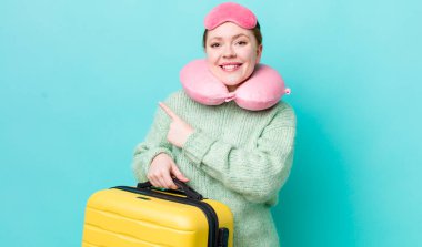 Kızıl saçlı güzel bir kadın neşeyle gülümsüyor, mutlu hissediyor ve bir tarafı işaret ediyor. uçuş yolcu kavramı