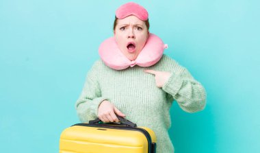 Kızıl saçlı güzel kadın şok olmuş ve ağzı açık, kendini işaret eden bir şekilde şaşırmış görünüyor. uçuş yolcu kavramı