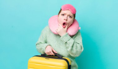 Kızıl saçlı, ağzı ve gözleri açık, eli çenesinde güzel bir kadın. uçuş yolcu kavramı