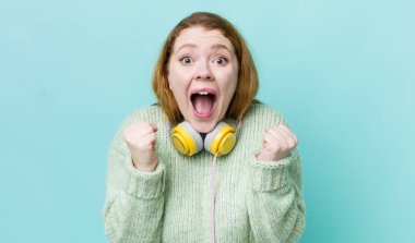 Kızıl saçlı güzel kadın şok olmuş hissediyor, gülüyor ve başarıyı kutluyor. Müzik konseptinin tadını