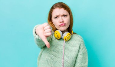 Kızıl saçlı, güzel bir kadın kendini kötü hissediyor, baş parmağını kaldırıyor. Müzik konseptinin tadını