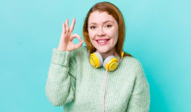 Kızıl saçlı güzel bir kadın kendini mutlu hissediyor. Onayını iyi bir hareketle gösteriyor. Müzik konseptinin tadını