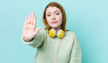 Kızıl saçlı güzel kadın ciddi görünüyor. Avuç içini gösteriyor. Durdurma hareketi yapıyor. Müzik konseptinin tadını