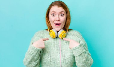 Kızıl saçlı güzel bir kadın mutlu hissediyor ve heyecanla kendini işaret ediyor. Müzik konseptinin tadını