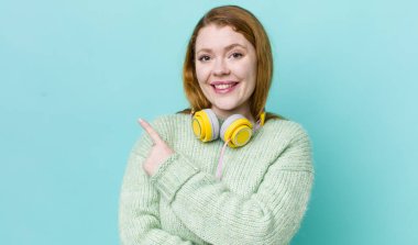 Kızıl saçlı güzel bir kadın neşeyle gülümsüyor, mutlu hissediyor ve bir tarafı işaret ediyor. Müzik konseptinin tadını
