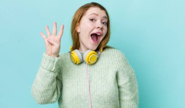 Kızıl saçlı güzel kadın gülümsüyor ve arkadaş canlısı görünüyor, dört numarayı gösteriyor. Müzik konseptinin tadını