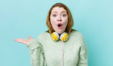 Kızıl saçlı, güzel bir kadın şaşırmış ve şok olmuş görünüyor. Çenesi düşmüş, elinde bir nesne var. Müzik konseptinin tadını