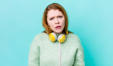 Kızıl saçlı güzel kadın şaşkın ve şaşkın hissediyor. Müzik konseptinin tadını