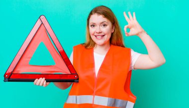 Kızıl saçlı güzel bir kadın kendini mutlu hissediyor. Onayını iyi bir hareketle gösteriyor. Araba üçgeni kazası.