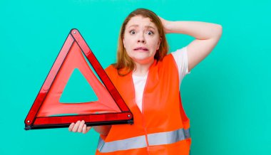 Kızıl saçlı güzel kadın stresli, endişeli ya da korkmuş, elleri başının üstünde. Araba üçgeni kazası.