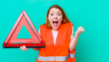 Kızıl saçlı güzel kadın şok olmuş hissediyor, gülüyor ve başarıyı kutluyor. Araba üçgeni kazası.