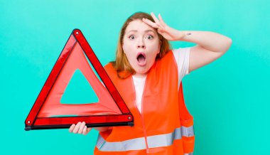 Kızıl saçlı güzel kadın mutlu, şaşkın ve şaşırmış görünüyor. Araba üçgeni kazası.