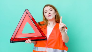 Kızıl saçlı güzel kadın gülümsüyor ve arkadaş canlısı görünüyor, bir numarayı gösteriyor. Araba üçgeni kazası.