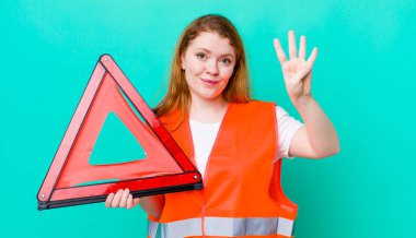 Kızıl saçlı güzel kadın gülümsüyor ve arkadaş canlısı görünüyor, dört numarayı gösteriyor. Araba üçgeni kazası.