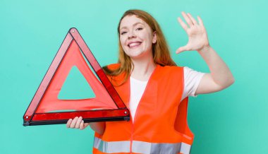 Kızıl saçlı güzel kadın gülümsüyor ve arkadaş canlısı görünüyor, beş numarayı gösteriyor. Araba üçgeni kazası.