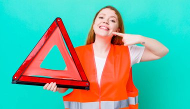 Kızıl saçlı, güzel bir kadın kendi gülüşünü işaret ediyor. Araba üçgeni kazası.